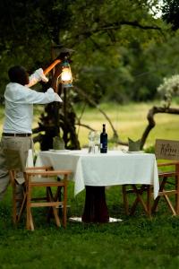 a man standing next to a table with a bottle of wine at Kipekee Zuri Camp in Ololaimutiek