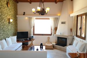 a living room with white furniture and a fireplace at Keramos Villa in Kerames