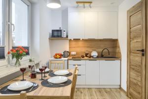 a kitchen with a table and chairs and a kitchen with white cabinets at Apartamenty Słoneczna in Tylicz +12 photos