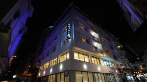 Un edificio alto de color morado con un cartel en él por la noche. en ARUBA BOUTIQUE HOTEL Casablanca, en Casablanca