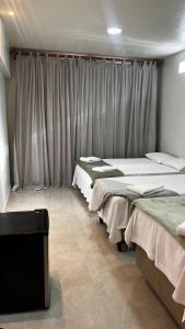 a group of beds in a room with curtains at Central Flats Jeri in Jericoacoara