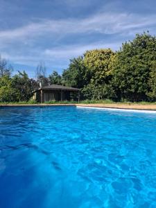uma piscina de água azul com uma casa ao fundo em Cabañas Candelaria em Los Ángeles