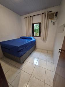 een slaapkamer met een blauw bed en een raam bij Condomínio Dell Mar in Bertioga