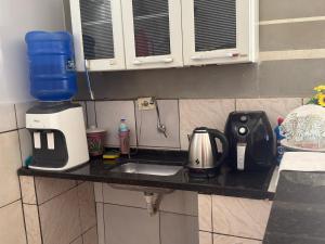 a kitchen counter with a sink and a blender at Suítes Santa Luzia in Trindade