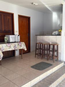 uma cozinha com um balcão e bancos num quarto em Suítes Santa Luzia em Trindade