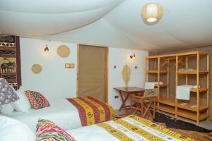 a bedroom with two beds and a desk and a table at Kipekee Zuri Camp in Ololaimutiek