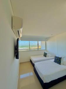 a hotel room with two beds and a window at Artsy Oceanview Condo W Incredible Rooftop Pool in Cartagena de Indias +18 photos