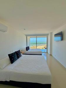 two beds in a bedroom with a view of the beach at Artsy Oceanview Condo W Incredible Rooftop Pool in Cartagena de Indias