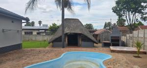 een zwembad in een tuin met een rieten dak bij Good night guest house in Polokwane