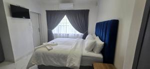 een slaapkamer met een bed met een blauw hoofdeinde en een raam bij Good night guest house in Polokwane