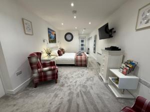 ein Schlafzimmer mit einem Bett, einer Couch und einem Stuhl in der Unterkunft Little Spinney Lodge in Saint Leonards