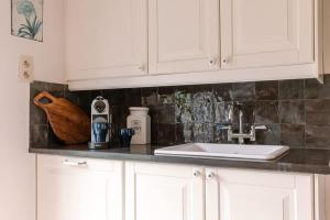 een aanrecht met een wastafel en witte kasten bij Villa - The Cozy Relax Home - Comfort Nature & Style in Beernem