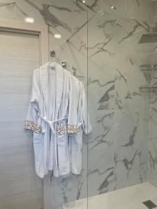 une robe blanche est suspendue dans une douche dans l'établissement Luxury Suite come al Four Seasons, à Paola