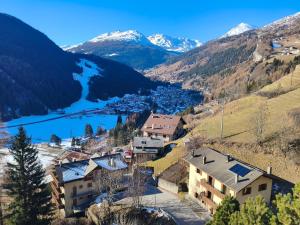 a village in the mountains with a river and snow covered mountains at Casa del Capitano Hilton in Isolaccia