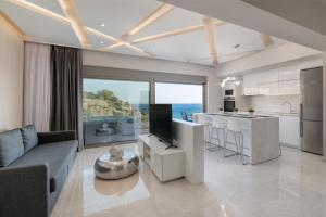 een keuken en een woonkamer met een bank en een televisie bij Aquamarine Luxury Suites - Stegna in Archangelos