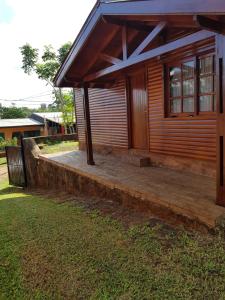 ein Holzhaus mit Veranda und Rasenfläche in der Unterkunft Cabaña del Iguazu in Puerto Iguazú