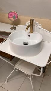 a white sink on a table with a mirror at Gîte Les Orchidées in Puyvendran