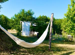 a hammock in a yard with a shed at Les Orchidées - Chambre in Puyvendran
