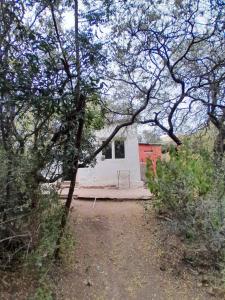 een klein wit gebouw midden tussen de bomen bij Monoambiente Magia Uritorco in Capilla del Monte