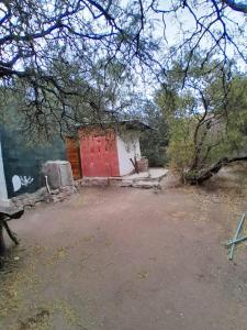 een gebouw met een rode deur in een veld bij Monoambiente Magia Uritorco in Capilla del Monte