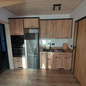 una cucina con mobili in legno e un frigorifero in acciaio inossidabile di Orkiszówka a Szczawnica