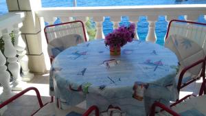 a table with a vase of flowers on a balcony at Apartments Gugic in Prigradica