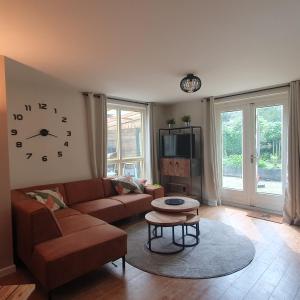 ein Wohnzimmer mit einer Couch und einer Uhr an der Wand in der Unterkunft 6 - Persoons Forest 217 Sauna Bungalow in Hernen