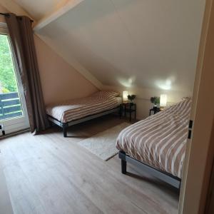 ein Schlafzimmer im Dachgeschoss mit zwei Betten und einem Fenster in der Unterkunft 6 - Persoons Forest 217 Sauna Bungalow in Hernen