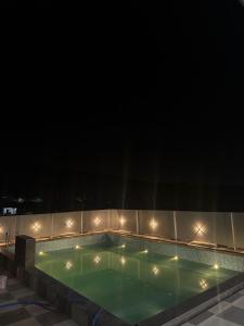 une piscine la nuit avec des lumières dessus dans l'établissement Rivana Retreat, à Dehradun