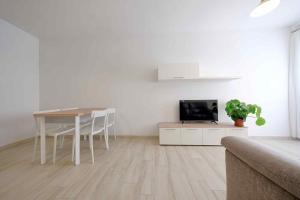un salon blanc avec une table et une télévision dans l'établissement Le Magie di Gioba, à Chia