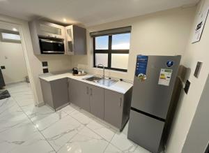 a small kitchen with a sink and a refrigerator at The Corner Guesthouse in Pietermaritzburg