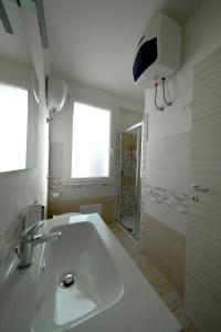 une salle de bain blanche avec lavabo et douche dans l'établissement Le Magie di Gioba, à Chia 9 autres photos