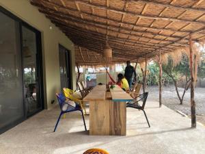 Eine Frau sitzt an einem Tisch mit Stühlen unter einem Dach in der Unterkunft Villa Palmarin Plage&Piscine in Palmarin