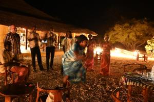 eine Gruppe von Menschen, die vor einem Feuer stehen in der Unterkunft Villa Palmarin Plage&Piscine in Palmarin