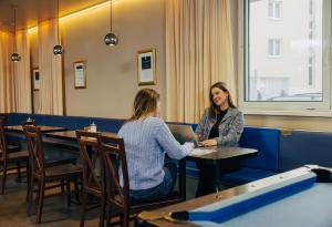 dos mujeres sentadas en una mesa con un portátil en MEININGER Hotel Wien Downtown Sissi, en Viena
