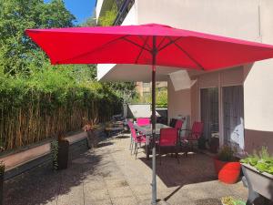 a red umbrella on a patio with a table and chairs at Bed & Breakfast Illchirch in Illkirch-Graffenstaden