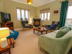 a living room with couches and chairs and a tv at Ash Corner Cottage in Weymouth