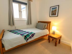 a bedroom with a bed and a table with a lamp at Ash Corner Cottage in Weymouth
