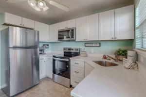 a kitchen with white cabinets and a stainless steel refrigerator at Paradise in the Palms in Mexico Beach