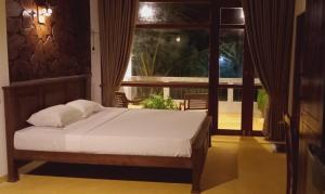 een slaapkamer met een bed en een groot raam bij Guruwaththa Eco Villa 3 in Hikkaduwa
