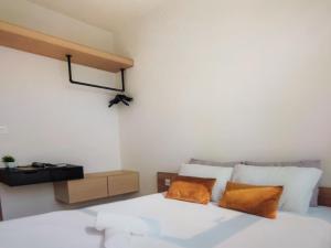 a bedroom with a white bed with two orange pillows at The Levana Home Saigon in Ho Chi Minh City
