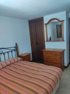 Un dormitorio con una cama, una cómoda y un espejo. en Casa Paulonia, en Las Negras