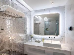 um banheiro branco com uma pia e um espelho em Qingdao Shandong Road Mixc Orange Crystal Hotel em Qingdao mais 40 fotografias