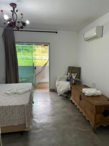 瓜拉派瑞Pousada Villa Felicidade的一间卧室设有两张床、一把椅子和一个窗户。