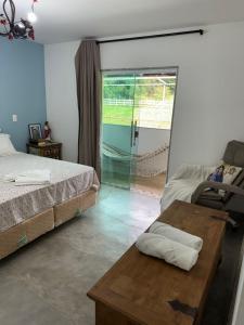 瓜拉派瑞Pousada Villa Felicidade的一间卧室，里面有一张床、一张桌子和一扇窗户