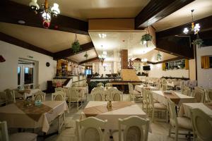 a restaurant with white tables and chairs in a room at Hotel Belvedere in Predeal