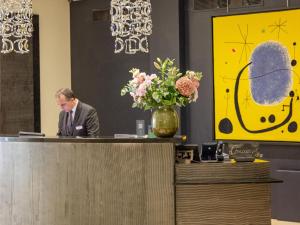 إدوارد 7 باريس أوبرا في باريس: رجل يجلس على مكتب الاستقبال وبجانبه مزهرية من الزهور