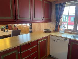 a kitchen with red cabinets and a white dishwasher at Nostalgic Cabin With 3 Br, Fireplace, And Terrace in Beitostøl