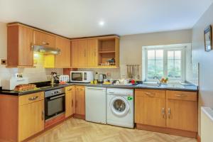 a kitchen with wooden cabinets and a washing machine at 2 Bed in Betws-y-Coed oc-84026 in Penmachno