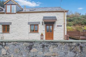a white cottage with a wooden door on a stone wall at 2 Bed in Betws-y-Coed oc-84026 in Penmachno